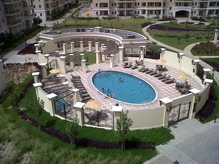 This image depicts a commercial landscaping project at an apartment complex with a pool next to pavers, grass and landscape edging from Permaloc.